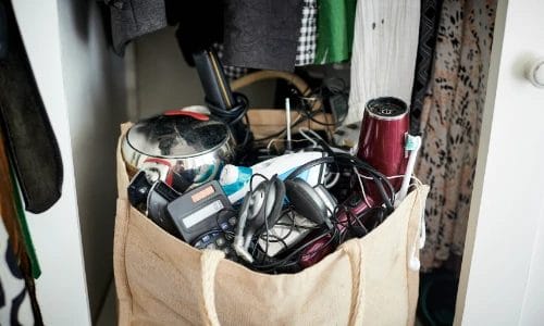 a hessian bag stuffed full of household electrical devices hanging in a wardrobe