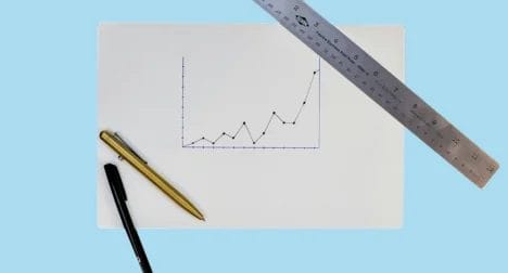 a top shot of a piece of paper with a graph drawn on it with two pens and a ruler next to it