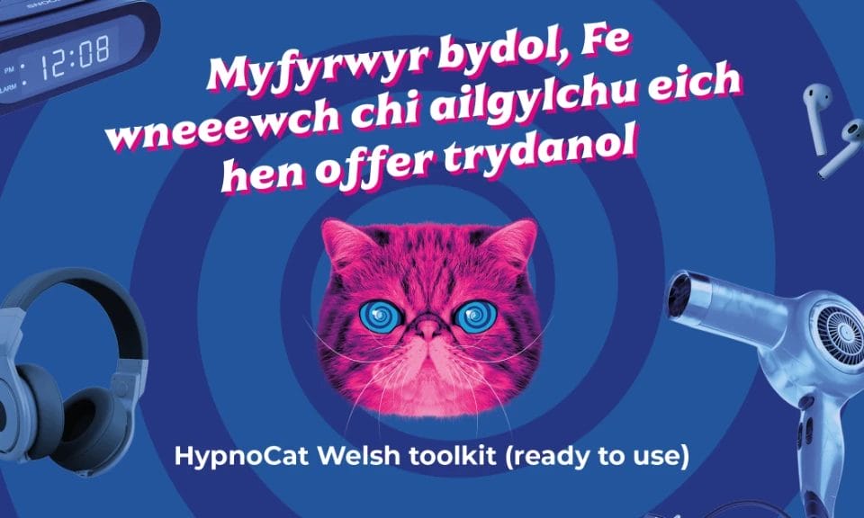 ‘HypnoCat’ (a magenta-coloured Persian cat with blue spiral eyes) surrounded by floating electricals with welsh text around him
