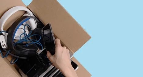 Photo shows a box being packed with electrical devices, cutout on blue background