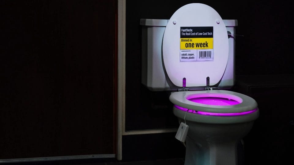 A white toilet with a pink light in the bowl a label saying "one week" is on the lid