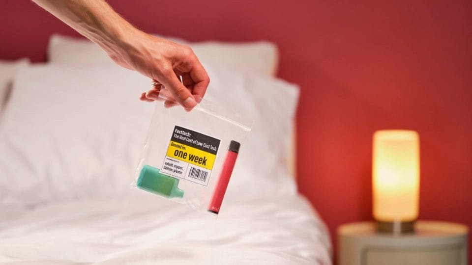 a pale skinned hand holding a clear plastic bag with an item of Fast Tech with writing saying "one week" on it