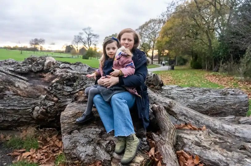 Bethan Taylor-Swaine and her daughter sitting on a cutdown tree in Brockwell Park, Herne Hill London